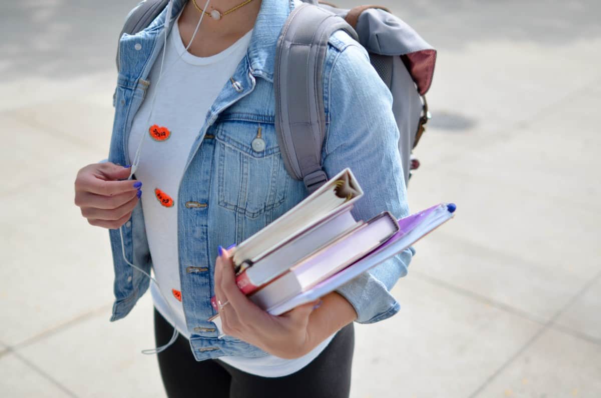 image of a college student in a blue jean jacket carrying books